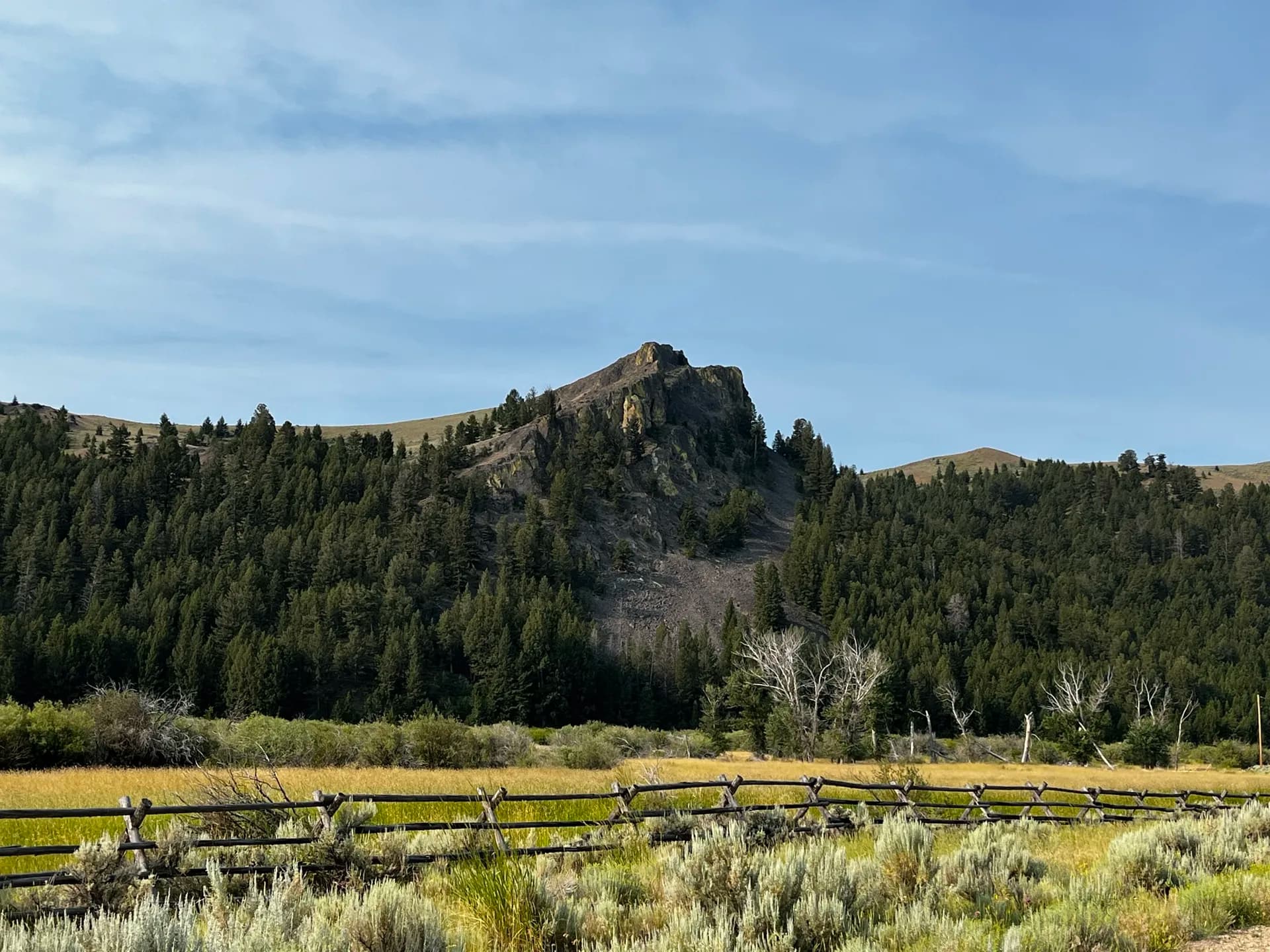Rocky peak above a Montana meadow and split-rail fence