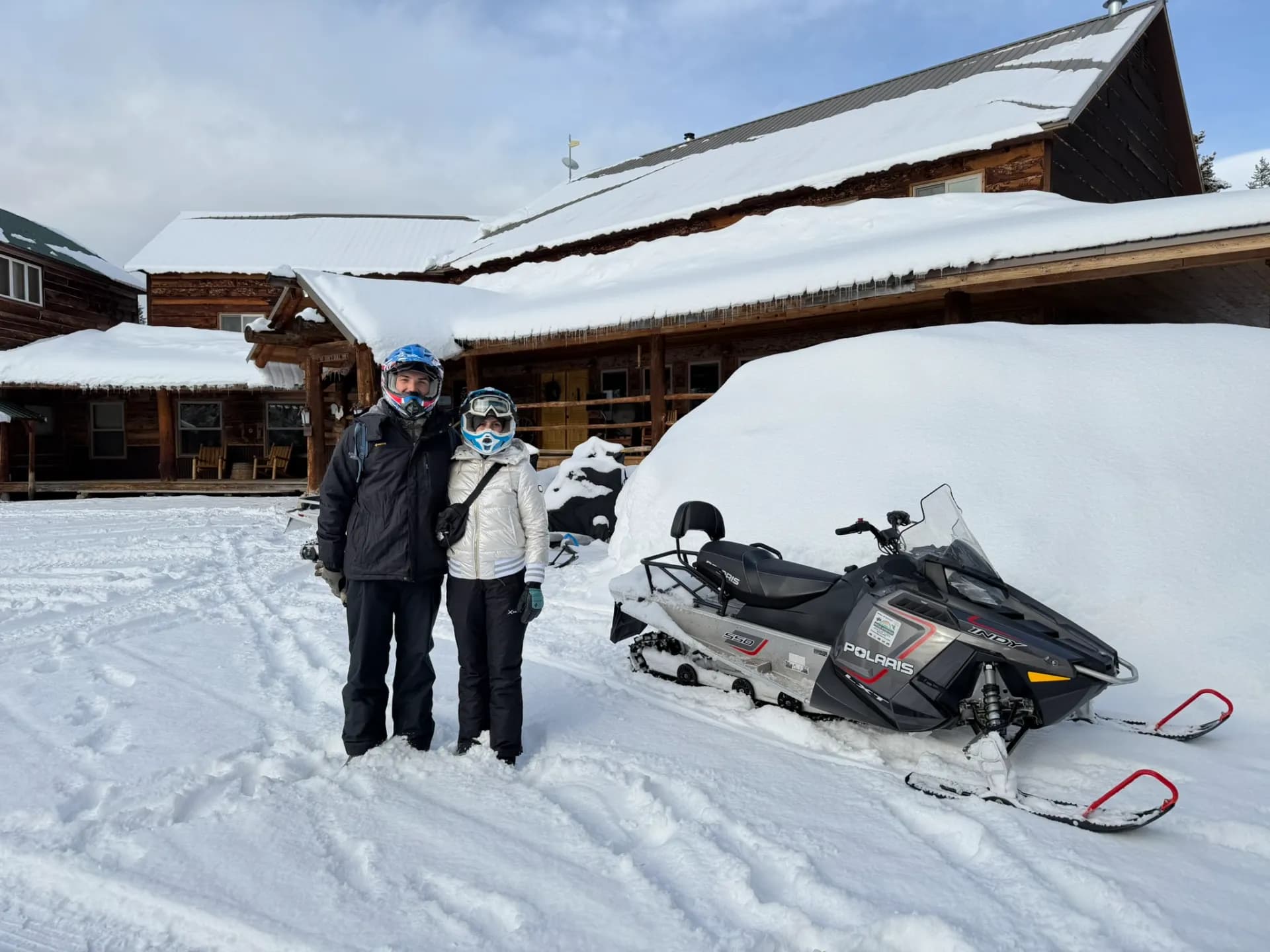 Riders with a Polaris snowmobile at a snowy lodge